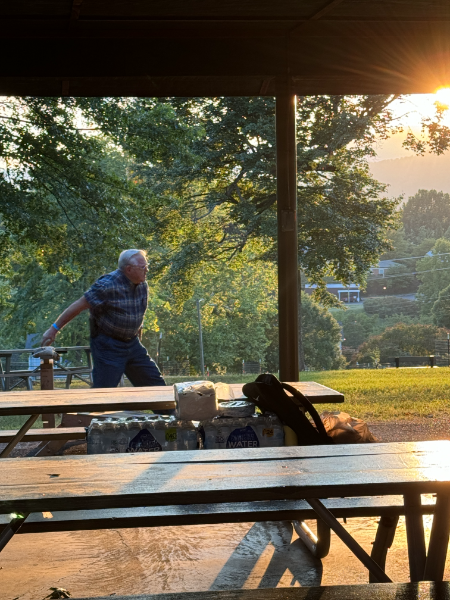 A man is standing at a picnic table in a park