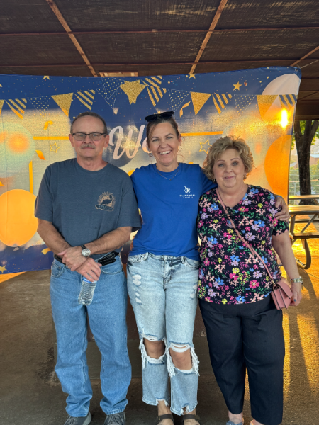 A man and two women are posing for a picture in front of a sign that says welcome