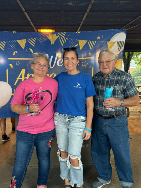 Three people posing for a picture in front of a sign that says welcome