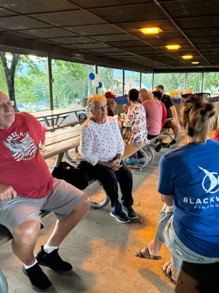 A man in a red shirt is sitting on a bench with other people