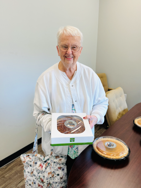 A woman in a white coat is holding a box of cake.