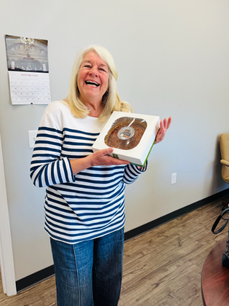 A woman in a striped shirt is holding a box of donuts
