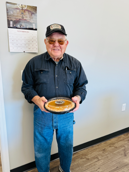 A man is holding a tray with a pie on it