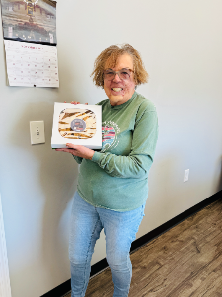 A woman in a green shirt is holding a box of donuts