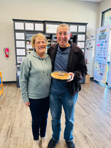 A man and woman standing next to each other holding a pie