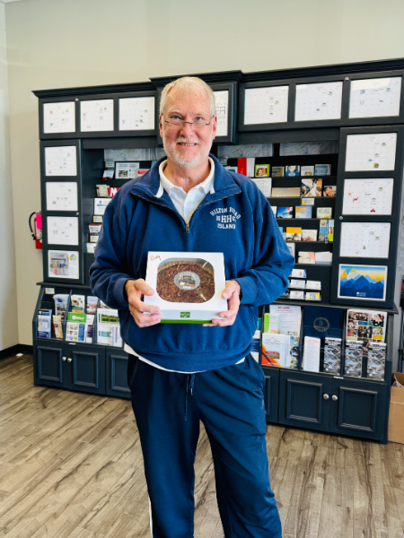 A man in a blue jacket is holding a box of donuts