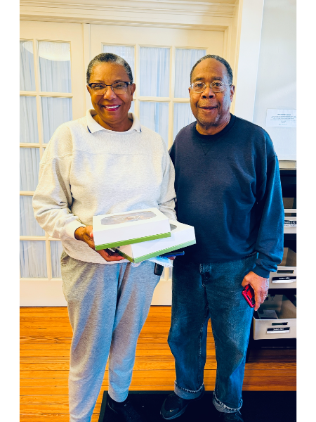 A man and a woman are standing next to each other holding boxes.