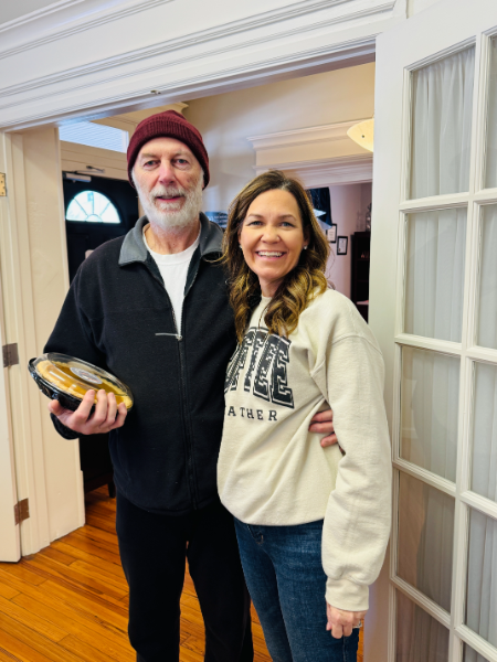 A man and a woman are posing for a picture while the man is holding a football.