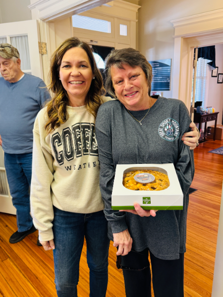 Two women standing next to each other with one wearing a coffe sweatshirt
