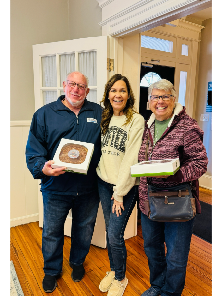 A man and two women are standing next to each other holding doughnuts