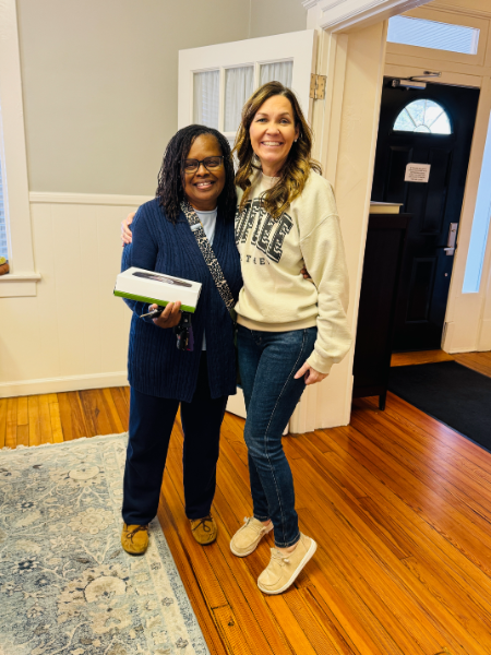 Two women are posing for a picture and one is wearing a sweater that says ' university ' on it