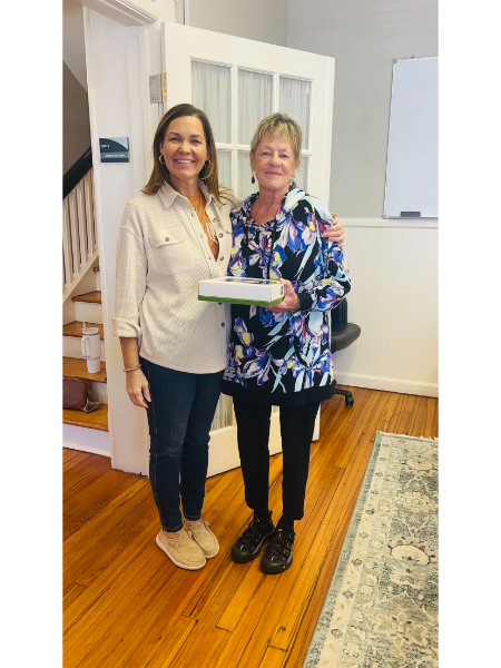 Two women are standing next to each other and one is holding a cake.