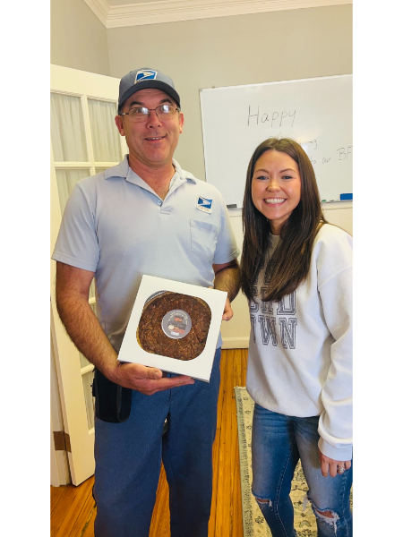 A man in a blue shirt is holding a box of brownies