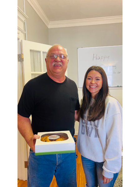 A man and a woman are standing next to each other holding a cake.