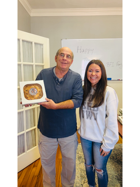 A man and a woman standing next to each other holding a box of food