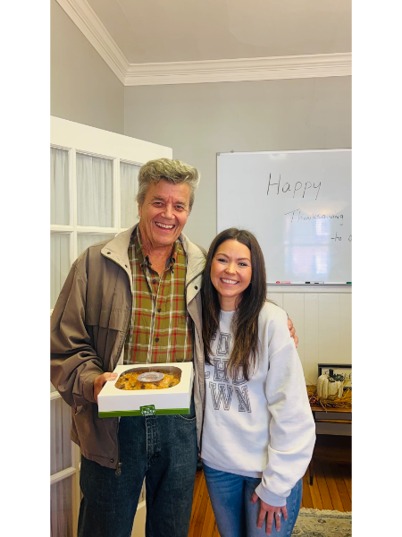 A man and a woman are posing for a picture while the man is holding a cake.