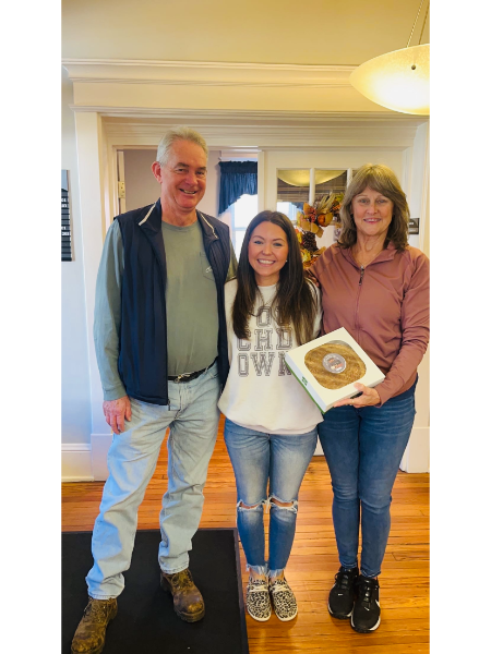 A man and two women are standing next to each other holding a donut.