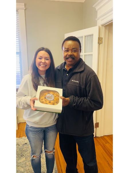 A man and a woman are standing next to each other holding a box of food.