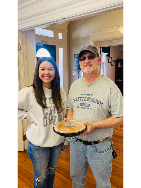 A man and a woman standing next to each other holding a pie