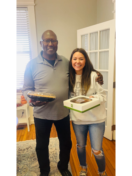 A man and a woman are standing next to each other holding boxes of food.