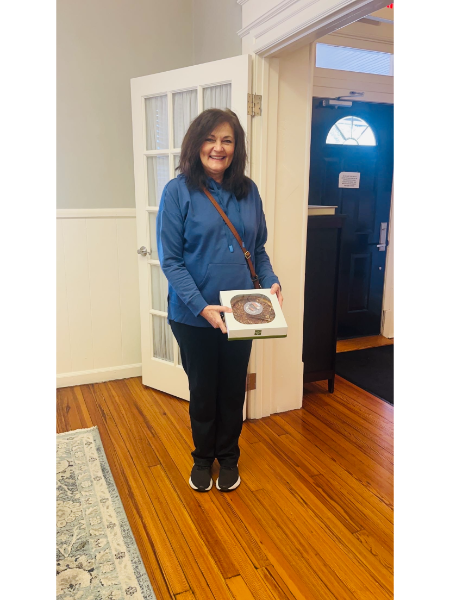 A woman in a blue shirt is holding a box of donuts