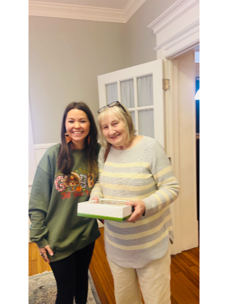Two women are standing next to each other in a room and one is holding a box.