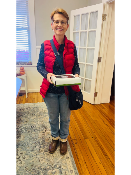 A woman in a red vest is holding a box