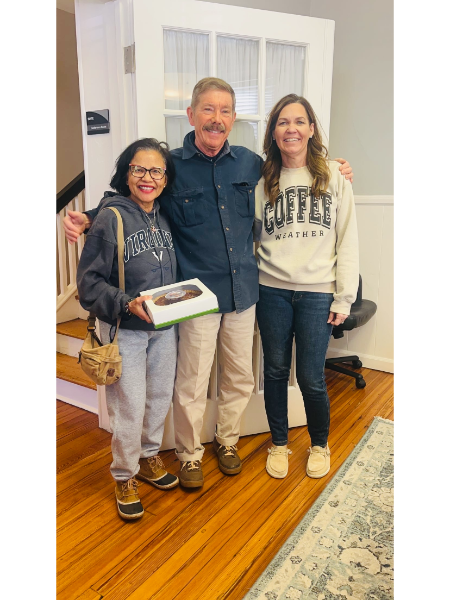 A man and two women are posing for a picture in a living room