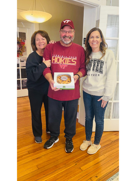 A man wearing a shirt that says hories is holding a donut