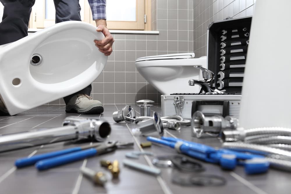 A Plumber Is Installing a Toilet in A Bathroom — Blair Merlehan Plumbing in Wagga Wagga, NSW
