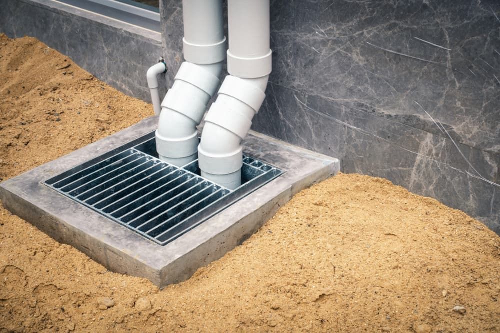 A Drain Pipe Is Sitting in The Dirt Next to A Building — Blair Merlehan Plumbing in Wagga Wagga, NSW