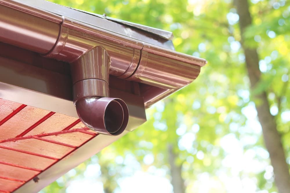 A Close up Of a Gutter on The Side of A House with Trees in The Background — Blair Merlehan Plumbing in Wagga Wagga, NSW