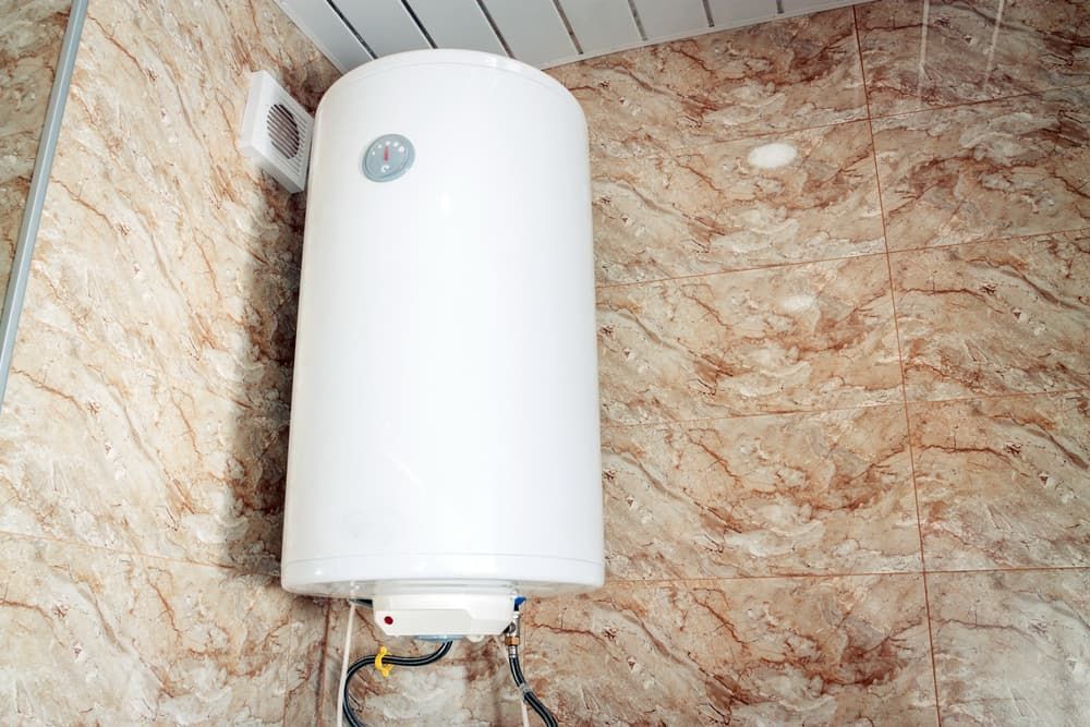 A White Water Heater Is Hanging on A Tiled Wall in A Bathroom — Blair Merlehan Plumbing in Wagga Wagga, NSW