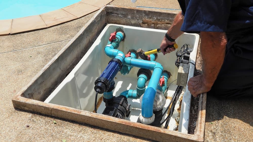 A Man Is Working on A Swimming Pool Pump — Blair Merlehan Plumbing in Wagga Wagga, NSW