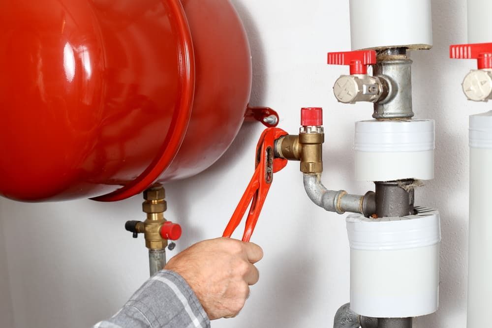 A Person Is Fixing a Pipe with A Wrench — Blair Merlehan Plumbing in Wagga Wagga, NSW