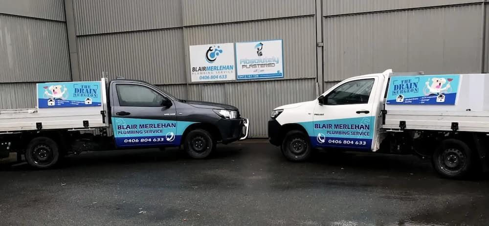 Two Trucks Are Parked Next to Each Other in Front of A Building — Blair Merlehan Plumbing in Wagga Wagga, NSW