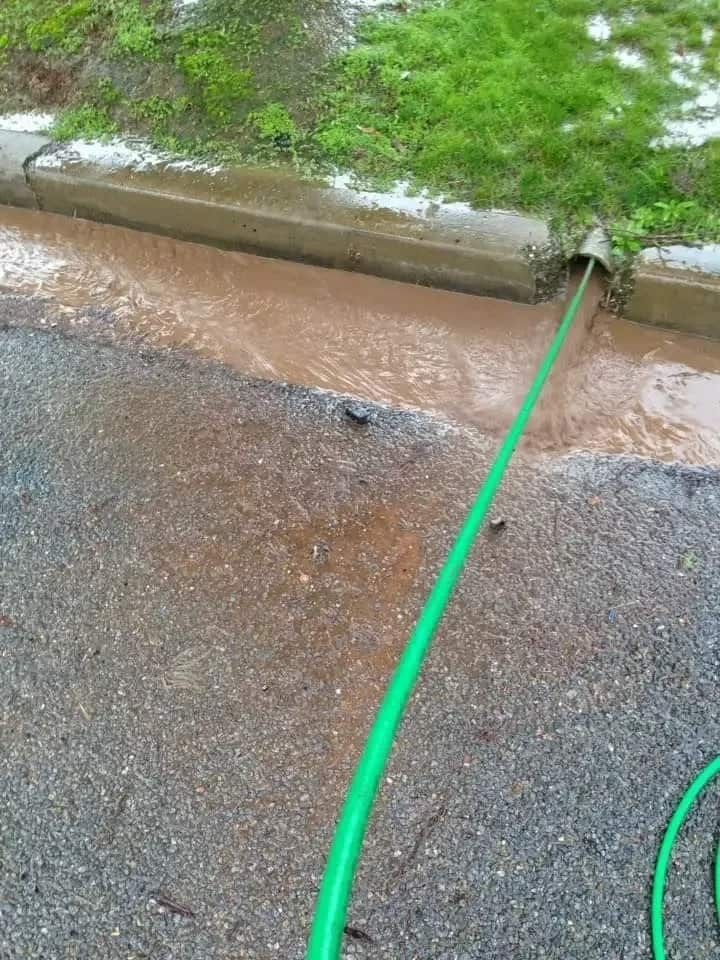 A Manhole Cover Is Being Cleaned by A Yellow Excavator — Blair Merlehan Plumbing in Wagga Wagga, NSW