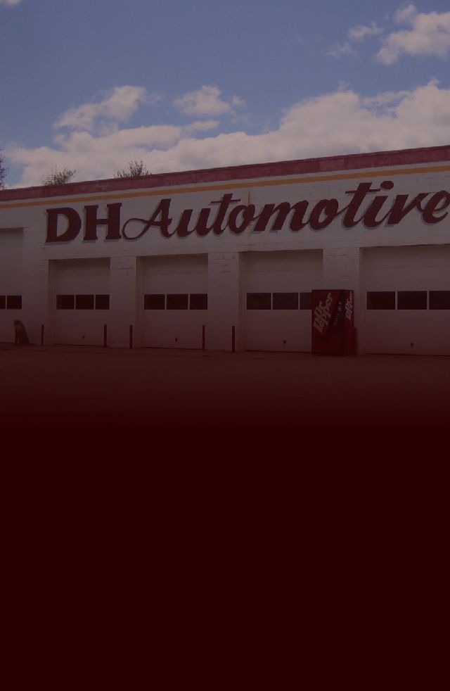 DH Automotive building with large sign and garage doors. Blue sky with clouds. | DH Automotive