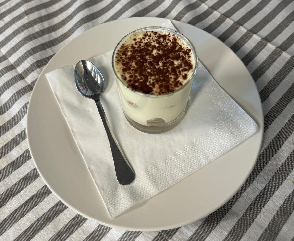 Un piatto bianco con un bicchiere di dessert e un cucchiaio sopra