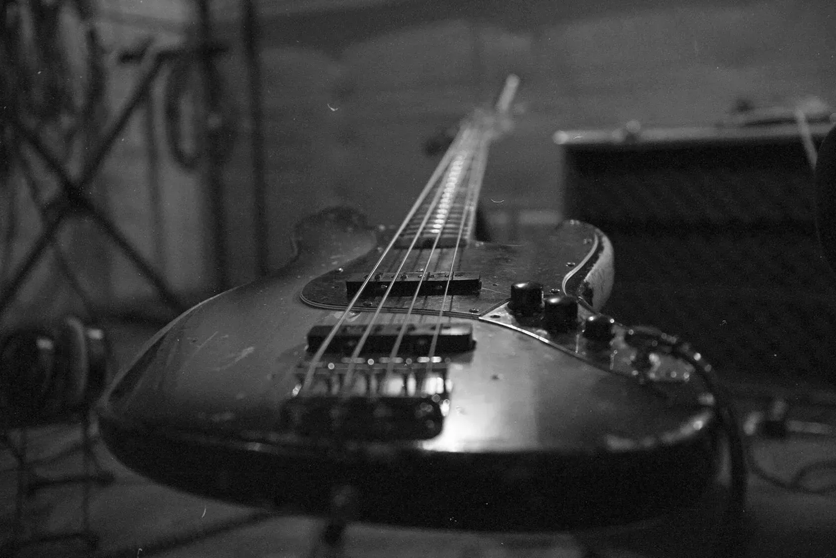 A black and white photo of a bass guitar on a stand