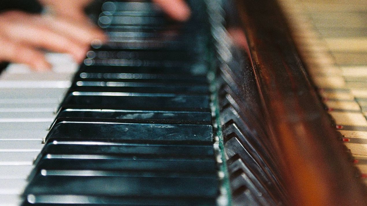 A person is playing a piano with their hands on the keys.