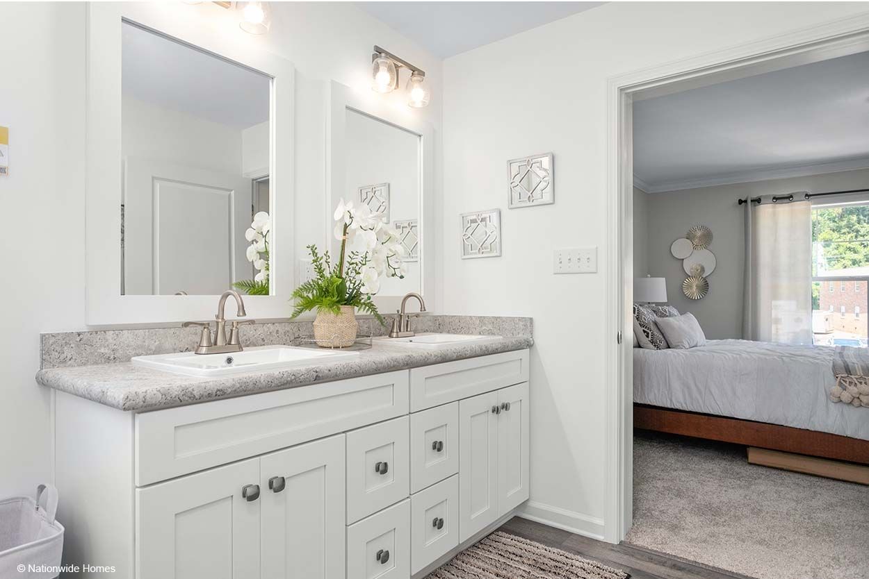 Modern bathroom with white cabinets, marble countertop, black faucets, and a shower with blue textured tile walls.