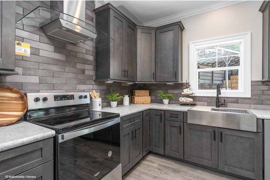 Modern kitchen with charcoal cabinets, gray brick backsplash, stainless steel appliances, and a farmhouse sink.