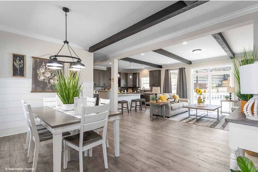 A smiling person with a mustache, wearing a blue button-down shirt, positioned in front of a gray wall.