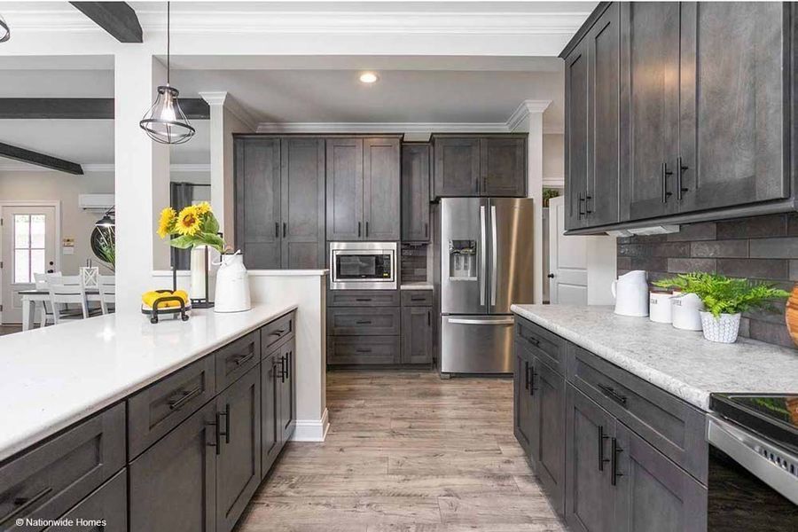 Modern kitchen featuring dark grey cabinets, stainless steel appliances, white countertops, and wood-look flooring.