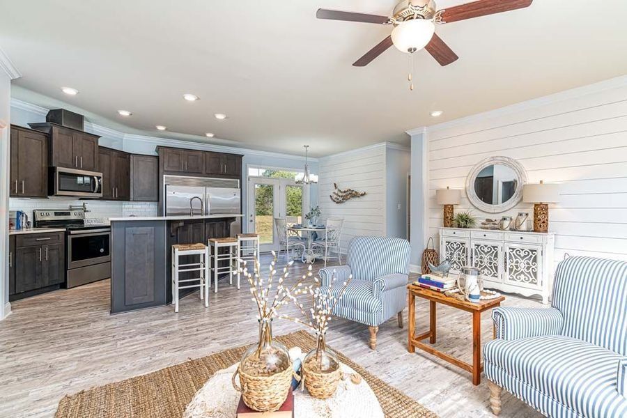 Open-concept kitchen and living area featuring dark wood cabinets, a kitchen island, and striped armchairs.