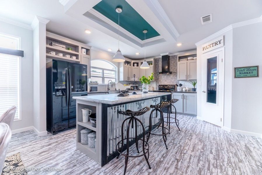 Modern farmhouse-style kitchen with a teal ceiling accent, grey cabinets, black appliances, and a central island.