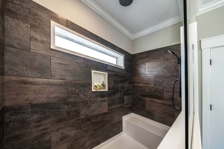 A modern shower featuring dark, textured wood-look tile walls, a horizontal rectangular window, and a built-in bench.