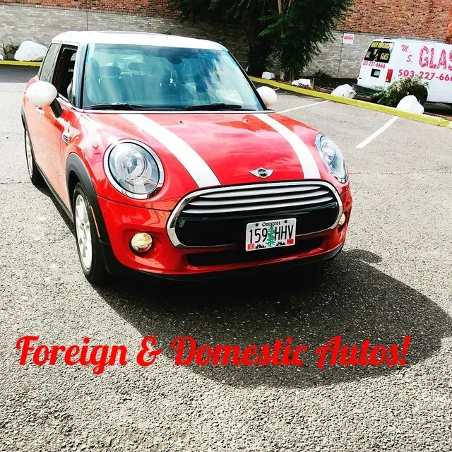 A red Mini Cooper with white racing stripes parked in an outdoor lot, with text overlaid reading Foreign & Domestic Autos!