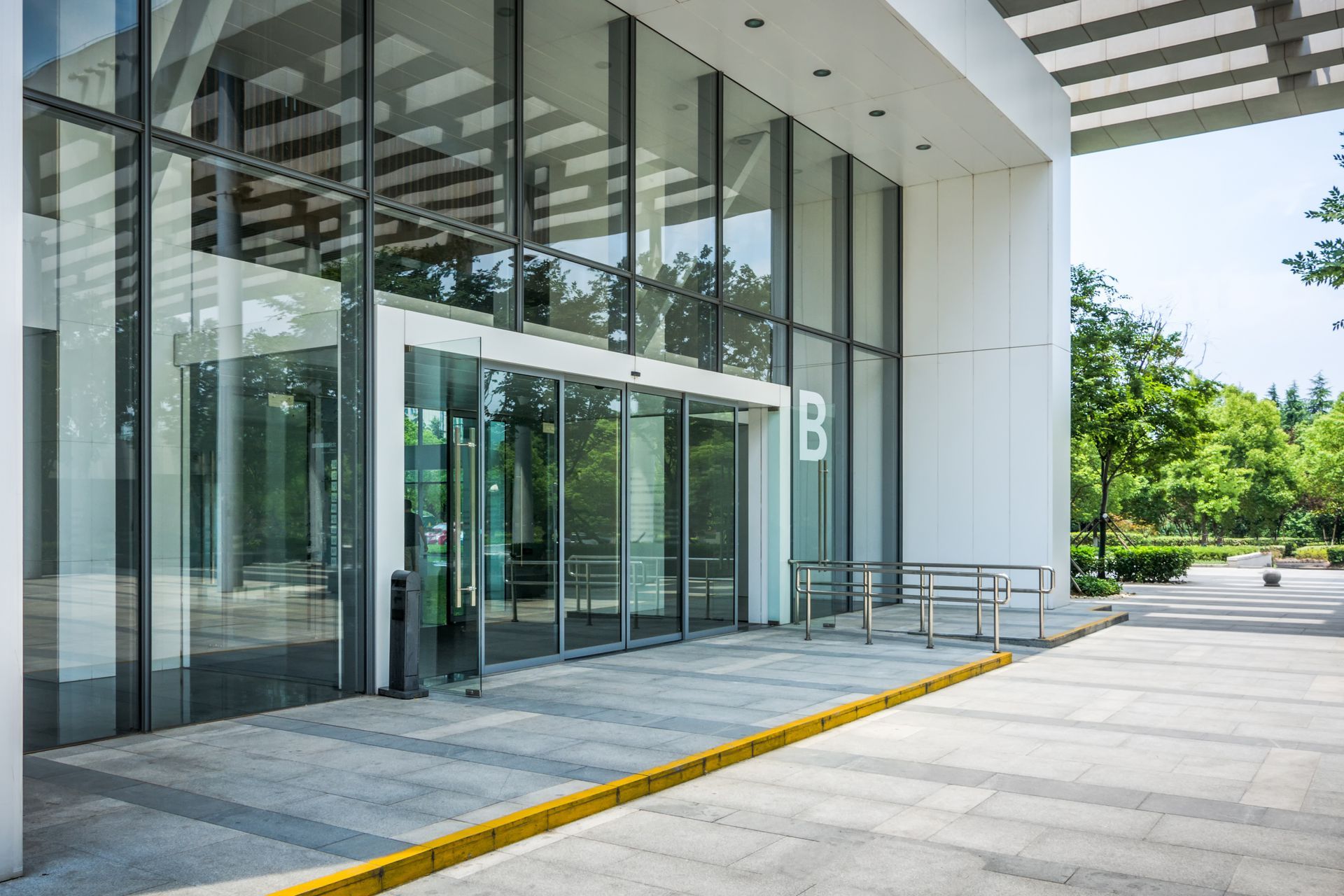 Modern building entrance with large glass walls, sliding doors marked 